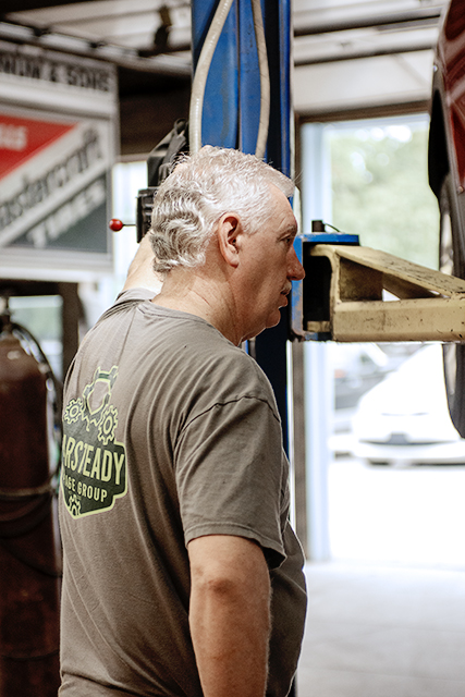 Veteran technician inspecting a vehicle on the lift before engine repair