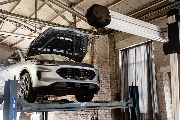 SUV raised on a lift with the hood open for engine service in Covington, IN