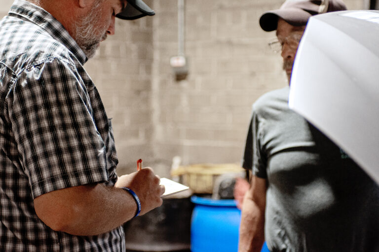 Newnum & Sons team reviewing a vehicle inspection in the shop