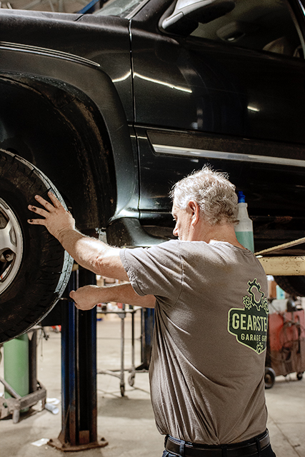 Newnum & Sons technician inspecting a wheel and tire on a vehicle lift