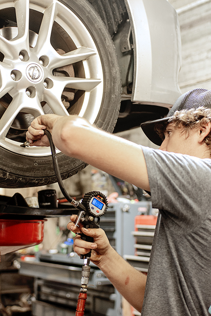 Technician checking tire pressure with a gauge during routine maintenance