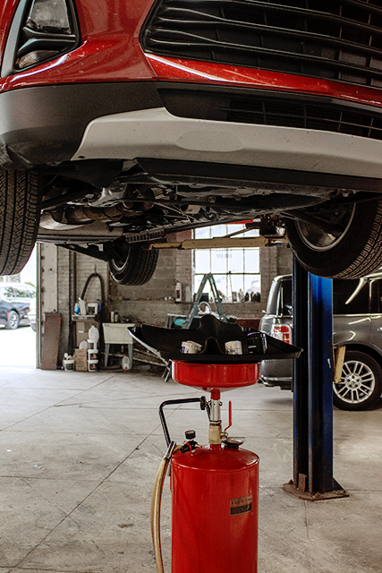 Maintenance bay with a vehicle raised and a fluid drain ready at Newnum & Sons Garage